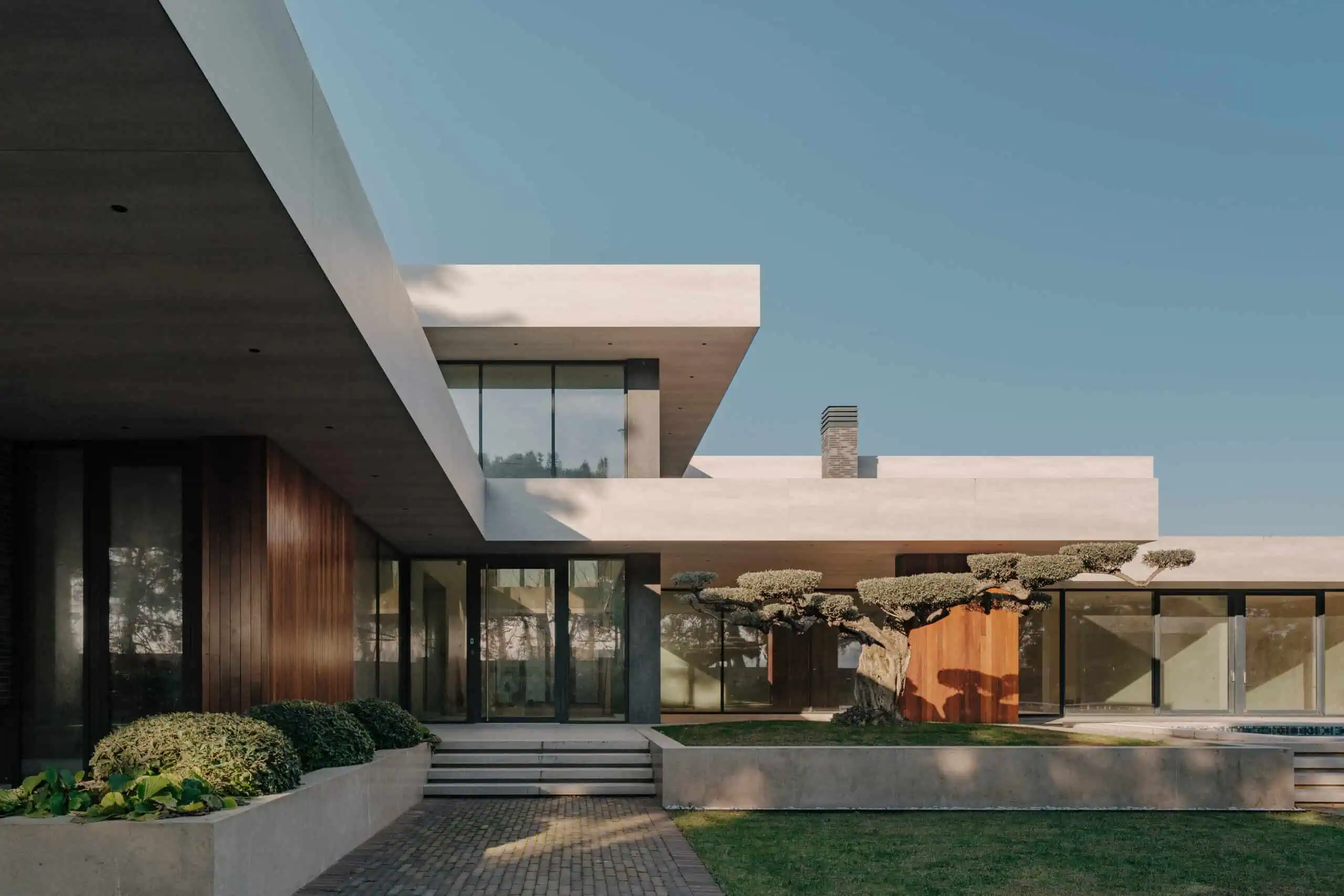 Contemporary modern house exterior with sleek design, large glass windows, and landscaped garden.