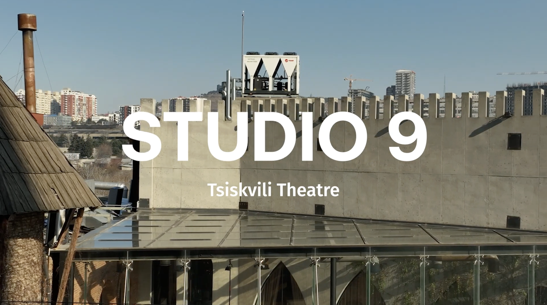 Modern theater building with city skyline in the background, showcasing vibrant cultural venue at Tsiskvili Theatre.