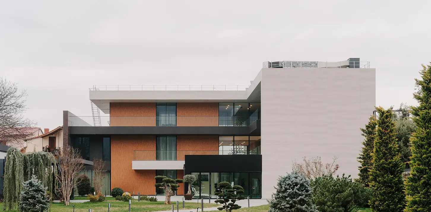 Modern multi-story residential building with contemporary architecture and landscaped garden.