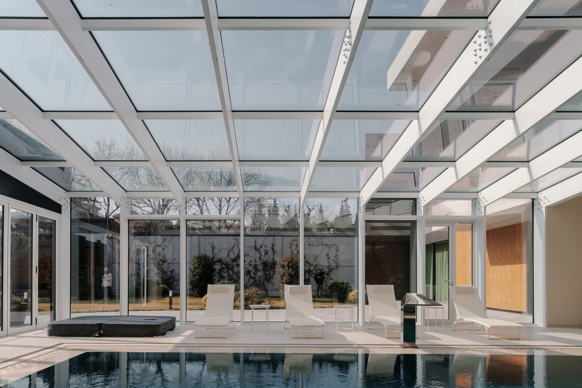 Indoor pool with glass ceiling and lounge chairs in a private house.